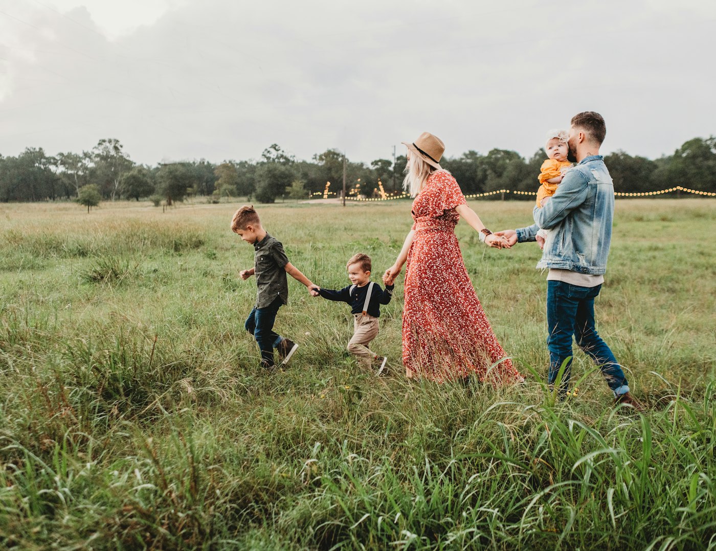 A family holding hands as they walk through a grassy field